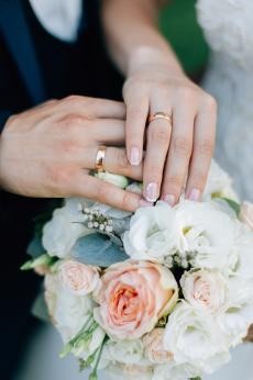 Zwei Hände mit jeweils einem Ehering, Blumenstrauß